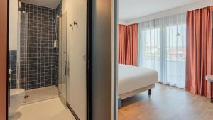 a bedroom with a bed and a shower and a bathroom at KYRIAD DAX - Saint Paul lès Dax in Saint-Paul-lès-Dax