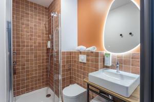a bathroom with a sink and a toilet and a mirror at KYRIAD DAX - Saint Paul lès Dax in Saint-Paul-lès-Dax +56 photos