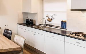 cocina con armarios blancos, fregadero y mesa en Grote Wiedenwoning 6P, en Giethoorn