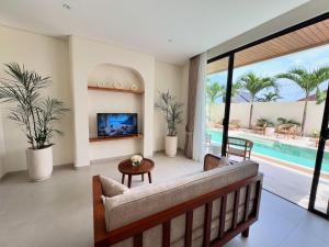 a living room with a couch and a tv and a pool at Lumix Residence in Munggu