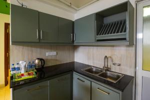 a kitchen with green cabinets and a sink and a microwave at Thilhara Colombo in Colombo
