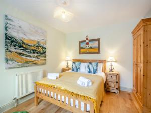 a bedroom with a bed and a painting on the wall at Seascape Cottage in South Creake