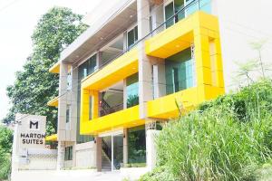 un bâtiment jaune et blanc avec un panneau devant lui dans l'établissement Marton Suites, à Sanghay