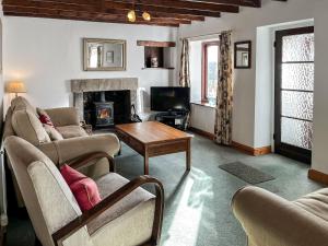 a living room with couches and a table and a fireplace at Butterfield Cottage in Tideswell