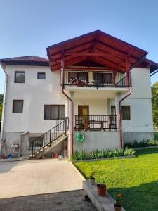 a white house with a porch and a balcony at Casa M&M in Vişeu de Sus +22 photos