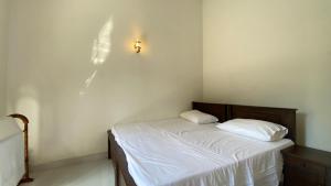 a bedroom with a bed with white sheets and a light on the wall at Villa Lee Polhena in Matara
