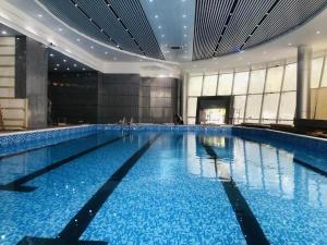 a large swimming pool with blue water in a building at Fenggang Gladden Hotel in Tiantangwei