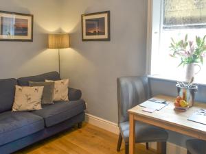 a living room with a blue couch and a table at Bluebell Cottage in Alnwick