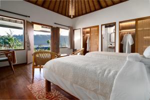 a bedroom with a bed and a chair and windows at Kibubu Forever Bali in Bedugul