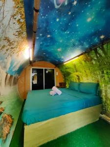 a bed in a room with a painting of the stars at Desaland Tunas Hijau in Labuan