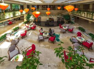 Un vestíbulo con sillas y mesas rojas y linternas naranjas. en Huangshan International Hotel, en Huangshan