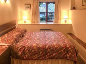 un dormitorio con una cama y una ventana en Forge Mill Cottage, en Dalbeattie