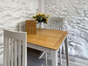 a white dining room table with a vase of flowers on it at 1 Bronrallt in Penmaen-mawr