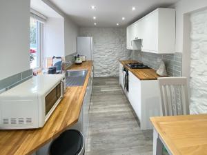 a kitchen with white cabinets and a sink and a microwave at 1 Bronrallt in Penmaen-mawr