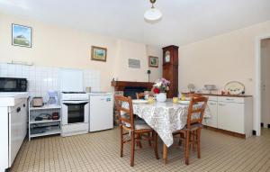 a kitchen with a table with chairs and a kitchen with white appliances at Beautiful Home In Andouillé-Neuville in Andouillé-Neuville