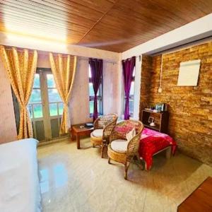 a room with chairs and a table and windows at Mension Inn in Cherrapunji