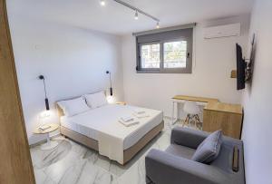 a white bedroom with a bed and a chair at The Angeliki Boutique Hotel in Skala Rachoniou +15 photos