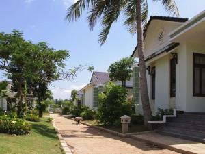 une maison avec un palmier à côté d'un trottoir dans l'établissement Sao Mai Phu My Resort, à Phú Mỹ