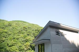 a building in front of a hill with trees at SEN RETREAT TAKIJIRI - Kumano Kodo Gateway in Tanabe