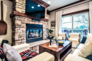 una sala de estar con chimenea de piedra en Le Plateau Ski Inout W 3bdrs W Pool Access, en Mont-Tremblant
