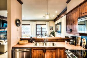 Una cocina con gabinetes de madera y un fregadero. en Le Plateau Ski Inout W 3bdrs W Pool Access, en Mont-Tremblant