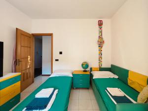 two beds in a room with a green couch at Villa Cannizzaro in Catania