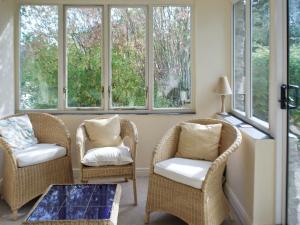 a living room with two chairs and windows at May Cottage in Bakewell