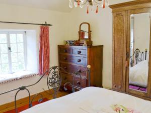 a bedroom with a bed and a dresser and a mirror at May Cottage in Bakewell