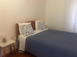 a bedroom with a bed with blue sheets and pillows at Sudoeste Guest House in Odeceixe