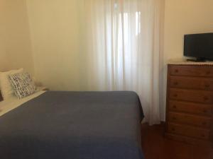 a bedroom with a bed and a dresser with a television at Sudoeste Guest House in Odeceixe