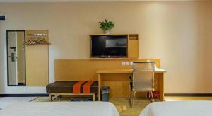 厦门7 Days Premium·Xiamen Airport Xianglu的酒店客房设有一张桌子和一台墙上的电视。