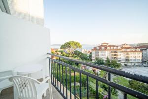 a balcony with a white chair and a view of a building at Hotel La Terraza in Sanxenxo
