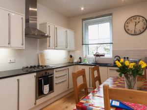 a kitchen with a table and a clock on the wall at Oystercatcher in Kingswear