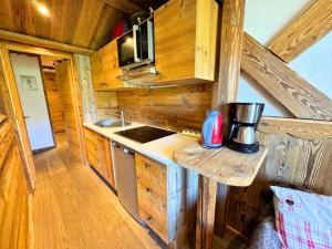 a kitchen with a stove and a sink in a log cabin at Résidence Necou - Studio déco style chalet en bord de pistes MAE-5954 in Les Menuires