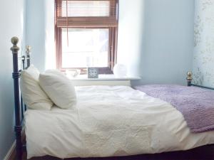 a bedroom with a white bed with a window at Poppy Cottage in Bonsall