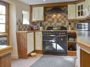 a kitchen with a black stove top oven at Poppy Cottage in Bonsall