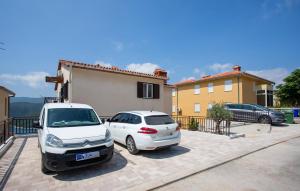 two cars parked in a parking lot in front of a house at Cozy Apartment In Rabac With Wifi in Rabac