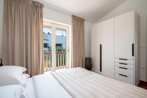 a white bedroom with a bed and a window at Marevita in Podstrana +44 photos