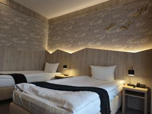 two beds in a hotel room with birds on the wall at Mikołajki Resort Hotel & Spa Jora Wielka in Mikołajki