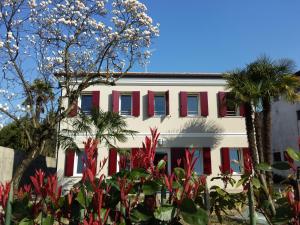 a white building with red shutters and palm trees at Villa Milu in Quinto di Treviso