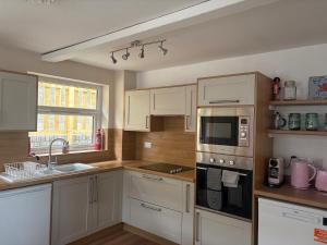 a kitchen with white cabinets and a sink at Amarons Nest - Cosy little house on Great Orme in Llandudno