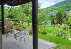 a swinging chair on a patio with a garden at Domek pod Zielonym Dachem in Rytro