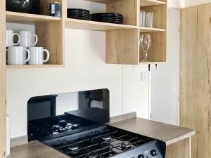 a stove top oven in a kitchen with wooden cabinets at Farne Lodge in Berwick-Upon-Tweed +5 photos