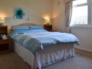 Un dormitorio con una cama con sábanas azules y una ventana. en Pleasant Spot Lodge, en Woolfardisworthy