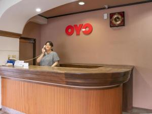 a woman standing behind a counter talking on a phone at Tabist Hotel Sankoen in Hitachi