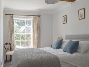 a white bed with blue pillows in a bedroom with a window at The Townhouse in Wimborne Minster