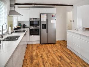 a kitchen with a stainless steel refrigerator and wooden floors at Barn Court in Rackheath +30 photos