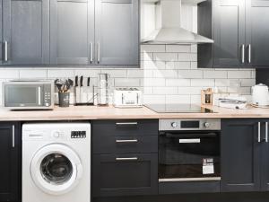 a kitchen with a washing machine and a microwave at Prospect Cottage in Catton