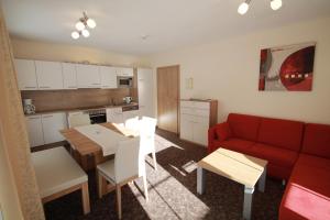 a living room with a red couch and a kitchen at Appartements Andy in Obergurgl