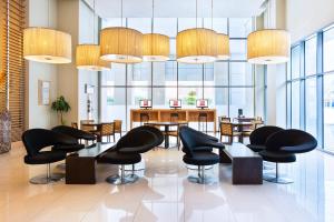 ドバイにあるIbis Deira Creekside Dubaiの黒い椅子とテーブル、窓のあるロビー